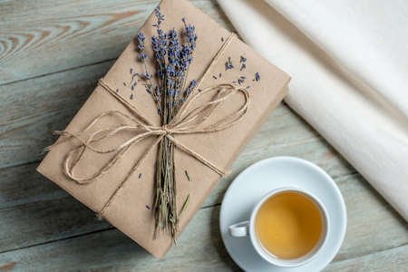 Neat stack of books with craft paper covers, wrapped in rope and decorated with lavender flowers, and a cup of tea on a wooden table. Concept of a cozy atmosphere for reading. Top view.の写真素材