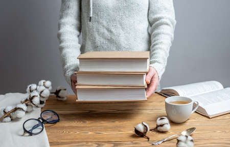 Woman is holding a stack of books wrapped in craft paper. Concept of reading, choosing a book and celebrating World Book Day.の写真素材