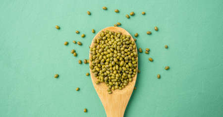 Asian beans in a wooden spoon on a green table. Concept of a proper balanced nutrition and healthy food.の写真素材