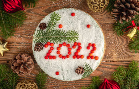 White holiday mousse cake covered with coconut flakes, imitating snow. On the cake, the number 2022 is put out in red berries. Concept of a New year.の写真素材