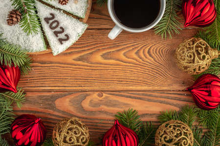 Card with a cup of coffee and white festive cake decorated with number 2022 made of chocolate. Concept of the New Year. Copy space.の写真素材