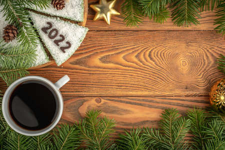 Card with a cup of coffee and white festive cake decorated with number 2022 made of chocolate. Concept of the New Year. Copy space.の写真素材