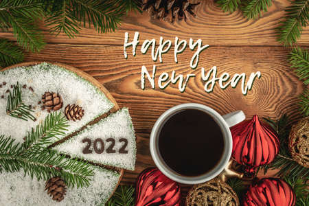 Card with a cup of coffee and festive cake decorated the number 2022 made of chocolate and the inscription Happy New Year. Top view.の写真素材