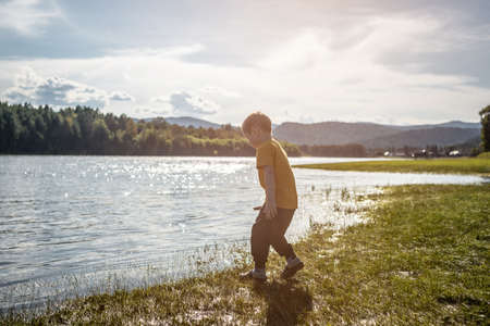 A child is playing by the river in a warm autumn forest. Concept of active recreation, spending time in nature, a family hike.の写真素材