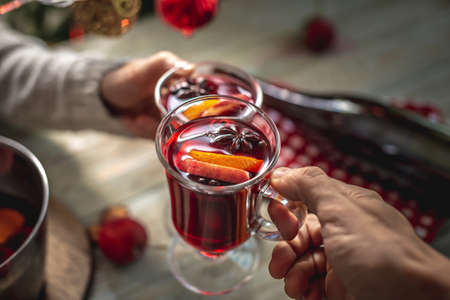 Man and a woman is drinking fragrant hot mulled wine in a cozy home festive atmosphere. Concept of New Year and Christmas mood. Closeup.の写真素材