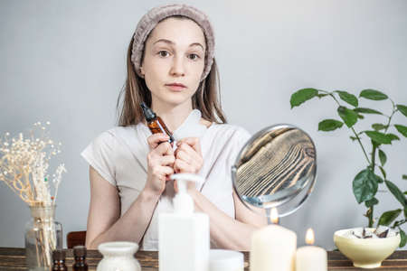 Young woman is holding a gouache scraper massager and a bottle of natural organic oil for massage...