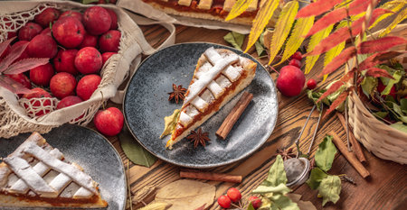 Appetizing homemade pie on a wooden table with garden apples, cinnamon and autumn leaves. Concept of a cozy atmosphere and autumn mood.の写真素材