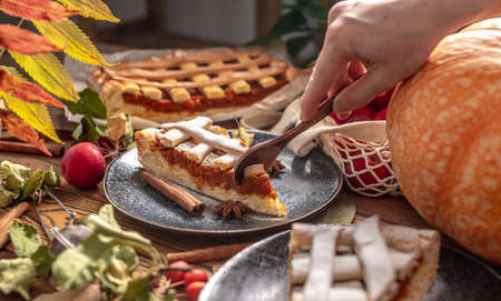 Hand of person is breaking off a piece of appetizing pie with a spoon. Concept of a warm and cozy autumn atmosphere with the aroma of fresh tasty pastries.の写真素材