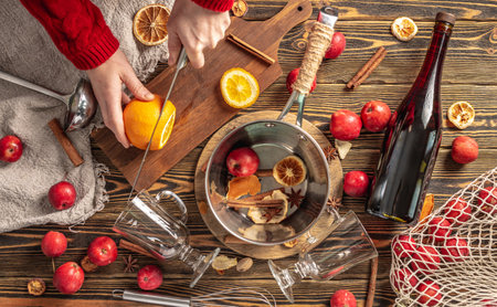 Woman is cutting oranges with a knife to cook mulled wine. Process of making a warming traditional drink, a cozy festive atmosphere. top viewの写真素材