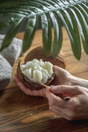 Hands of woman hold a bowl with fresh coconut oil and a wooden spoon. Concept of a healthy ingredient for cooking and natural cosmetics.の写真素材