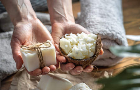 Hands of woman hold a bowl with fresh coconut butter and a piece of white handmade coconut soap. Concept of making and using natural soap and eco cosmetics, an interesting creative hobby.の写真素材