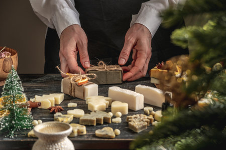 Woman is packing handmade natural soap as a gift for New Year and Christmas. Concept of preparing for holidays, hobbies, a cozy festive atmosphere.の写真素材