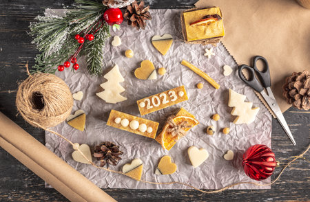 Card or wallpaper with Christmas decor, handmade soap with the number 2023, wrapping paper and ribbons. Concept of packaging gifts for the New Year and a festive mood.の写真素材