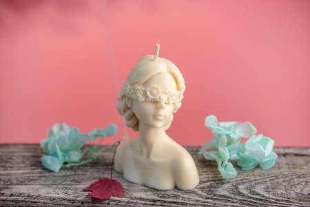 Beautiful handmade candle in the shape of a female body on a wooden table and the pink background.の写真素材
