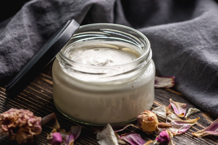 Natural fragrant cream or butter for body in a clear glass jar on a wooden background. Concept of organic cosmetics and skin care.の写真素材