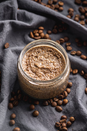 Organic oil scrub with sugar and coffee on the background of coffee beans on black cloth. Concept of natural cosmetics and skin care.の写真素材