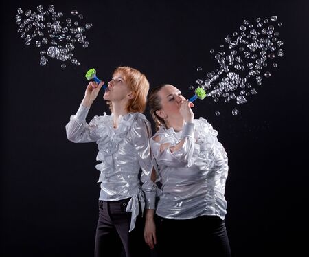 girl is doing soap bubble show on the black background