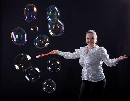 girl is doing soap bubble show on the black backgroundの写真素材