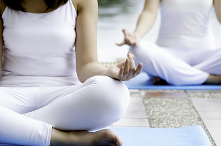 Two young women sitting as a yoga pose outdoorの写真素材