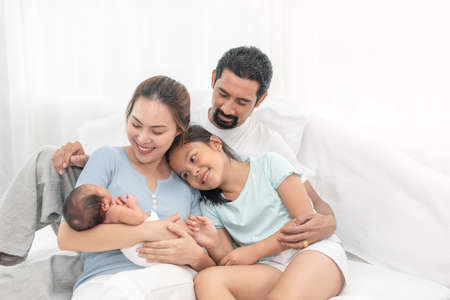 Parent and children relaxing together. Portrait of a young family with mother, father, son and daughter. Parents having happy time, welcoming newborn.の写真素材