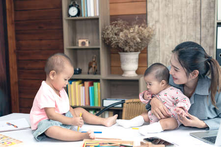 Busy woman trying to work while babysitting two daughter.