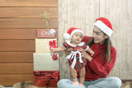 Merry Christmas and Happy Holidays! Cheerful mom and her cute 6 months daughter playing and have fun together.の写真素材
