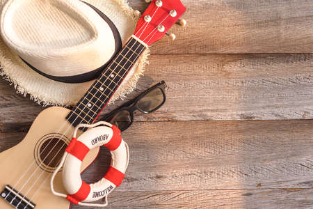 Top view sea travel concept. Summer hat, ukulele, sunglasses on wooden backgroundの写真素材