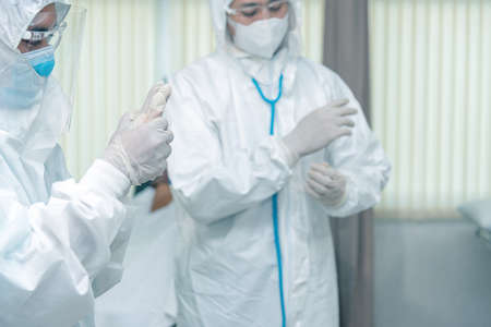 Doctors Surgeon in scrubs putting on surgical gloves. Doctors put on protective glove and mask and...