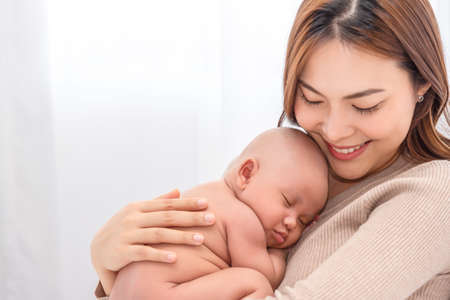 Close up beautiful young asian mother holding her newborn one month baby sleep on her lap....