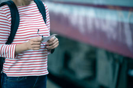 Selected focus on women hands holding a train ticker while standing on train platform waiting for...