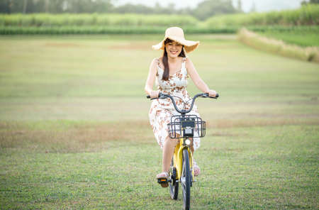 Young beautiful Asian woman riding a bicycle in a park. Active people. Pretty young woman riding bike in a country road.の写真素材