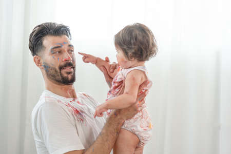 Young mix race father and Asian mother playing color painting with little baby cute girl. Family having happy time on the weekend.の写真素材
