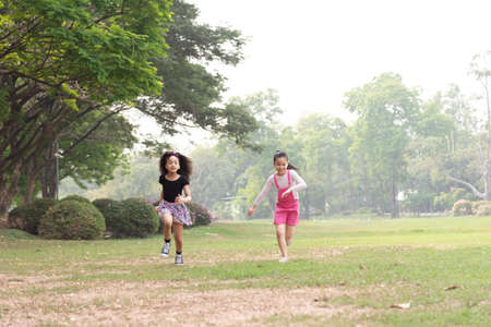 Small group of a happy children run through the park in the background of grass and trees. Children's outdoor games, vacations, weekend, Children's Dayの写真素材
