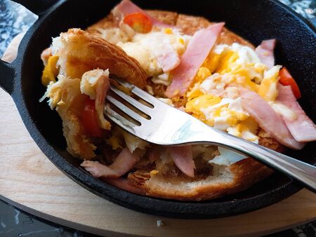 Pizza food, ham sausages, fried eggs, tomato sauce in a black pan.の写真素材