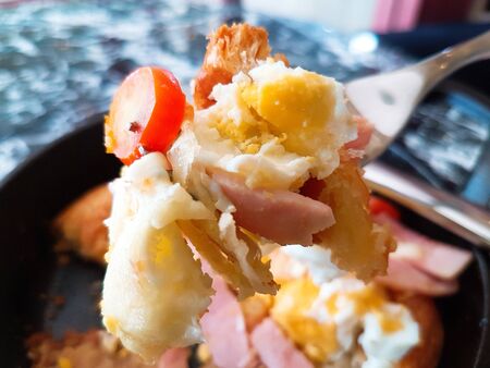 Pizza food, ham sausages, fried eggs, tomato sauce in a black pan.の写真素材