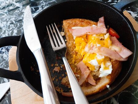 Pizza food, ham sausages, fried eggs, tomato sauce in a black pan.の写真素材