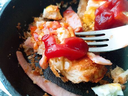 Pizza food, ham sausages, fried eggs, tomato sauce in a black pan.の写真素材