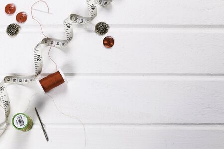 Flat lay of sewing equipment with cotton reels, buttons and measuring tape on a white background with space for text or design Christmas coloursの写真素材