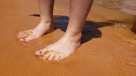 Bare feet with a pedicure on a beach vacationの写真素材
