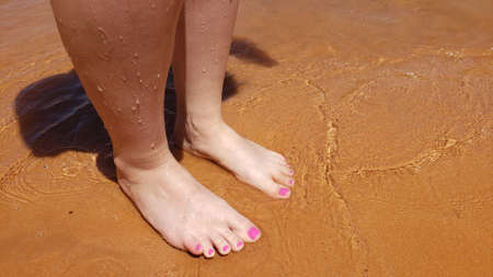 Bare feet with a pedicure on a beach vacationの写真素材