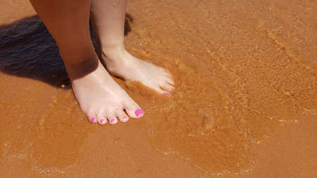Bare feet with a pedicure on a beach vacationの写真素材