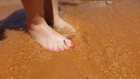 Bare feet with a pedicure on a beach vacationの写真素材