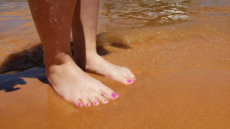 Bare feet with a pedicure on a beach vacationの写真素材