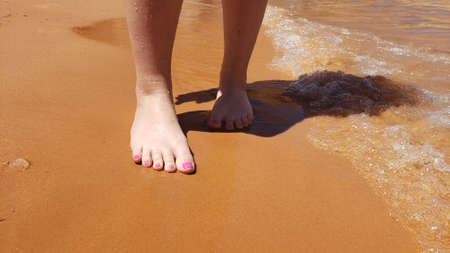 Bare feet with a pedicure on a beach vacationの写真素材