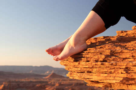Bare feet on a cliff overlooking a canyon at sunset