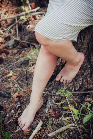 Female legs leaning up against the bark of a tree barefoot in natureの写真素材