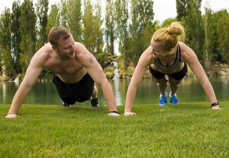 A man and woman holding the plank position of a pushup while looking at each other.の写真素材
