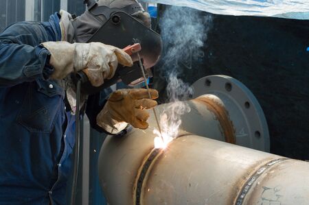 Welder wearing protective clothing for welding industrial construction oil and gas  at construction...
