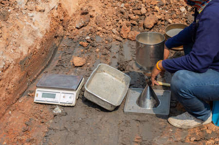 Worker using equipment for testing laboratory field density test sand cone method and soil density test of road under the construction.Soil field density test sand cone method calculation .の写真素材