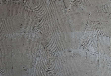 Gray wall glue plaster comb surface prepared for tiling.Tile adhesive notched trowel patterns....